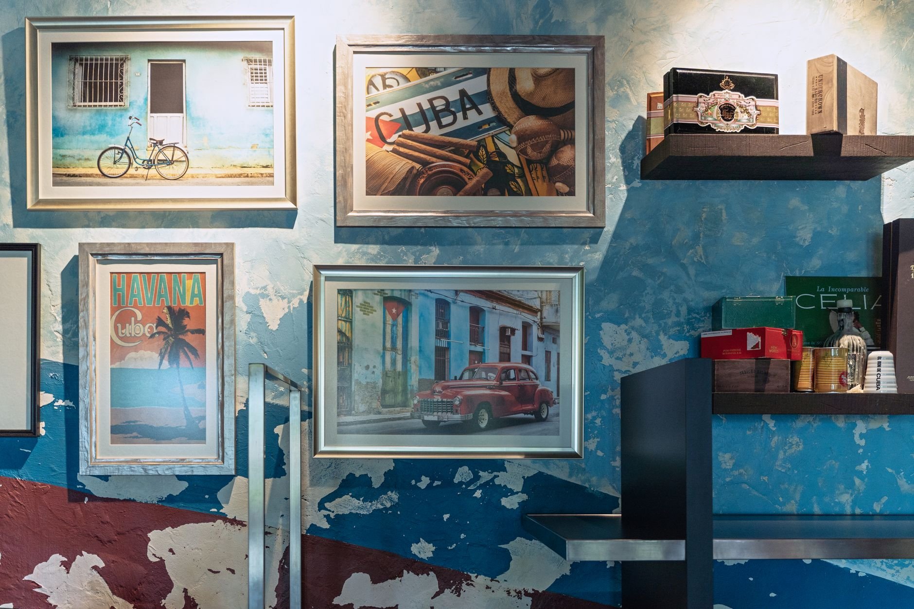 Cuban-themed framed art and decor on a textured blue wall for a vibrant interior look.
